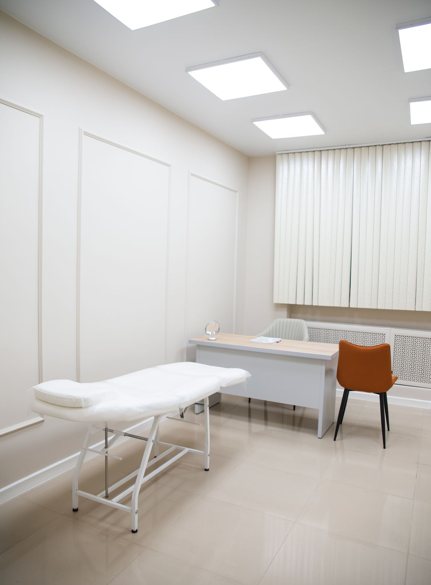 Sala de consulta clara con camilla, escritorio y silla