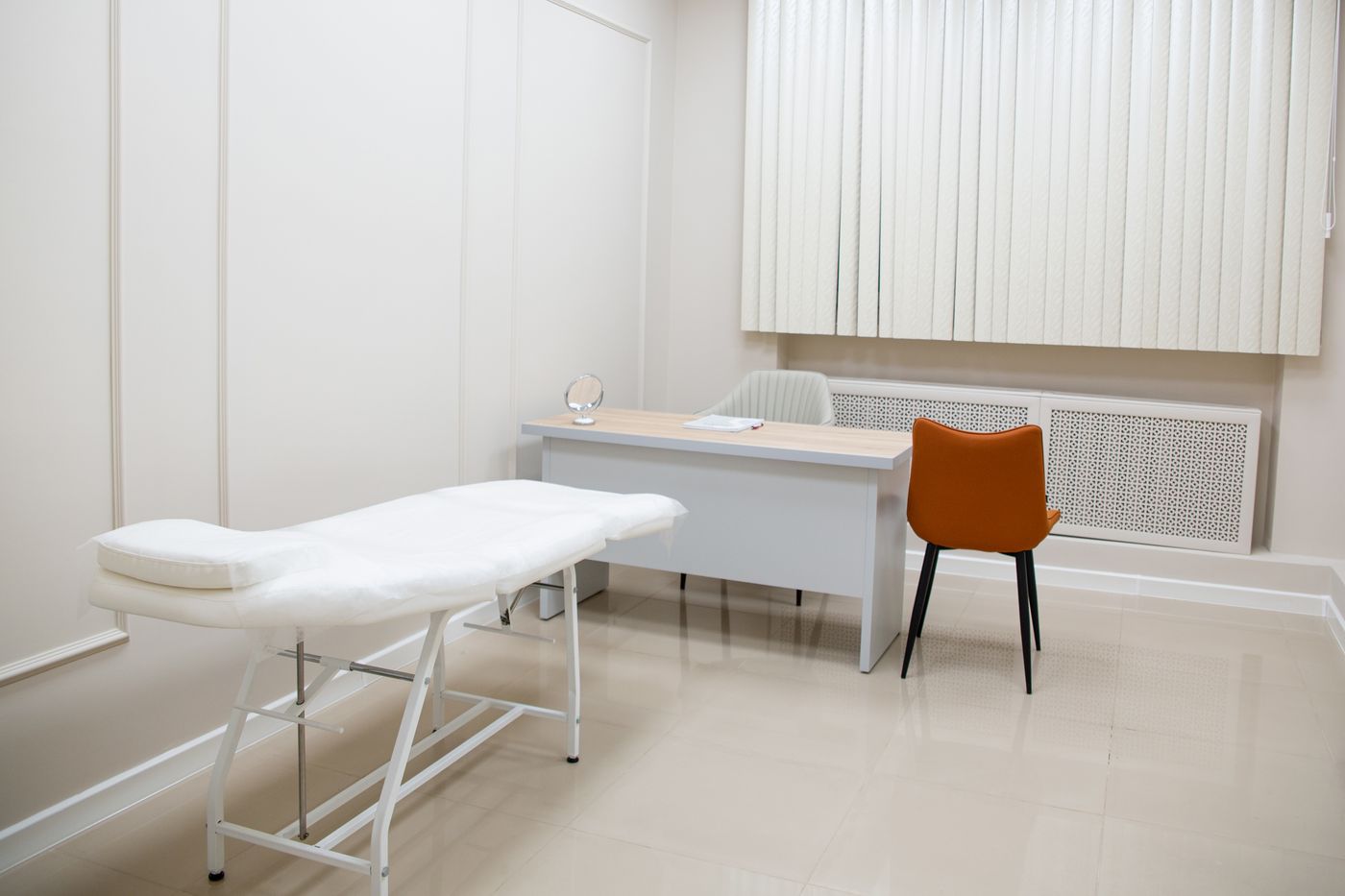 Sala de examen minimalista con escritorio, sillas y camilla